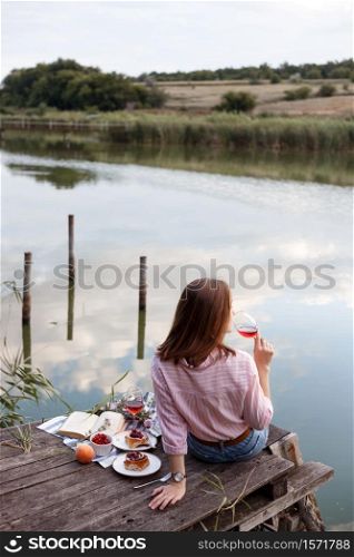 girl enjoying picnic on a wooden pier on a shiny summer river shore