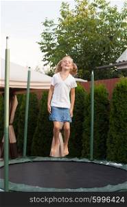 Girl enthusiastically jumping on the trampoline. Moment flight. Girl is jumping on batut
