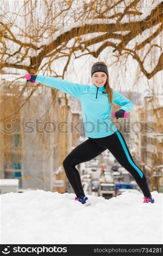 Girl exercising with dumbbells in city. Winter sports, outdoor fitness, fashion, urban workout, health concept.. Winter sports, girl exercising in city