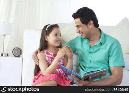 Girl explaining story to father on sofa at home