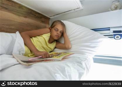 Girl fell asleep reading a magazine on the top shelf of a reserved seat car