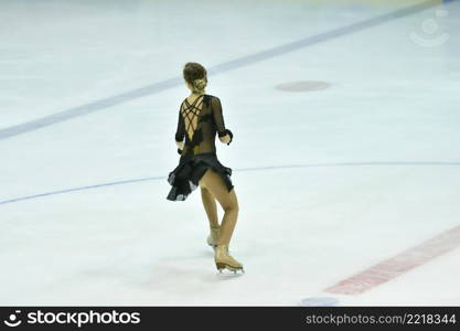 Girl figure skater rolls on a skating rink with artificial ice 