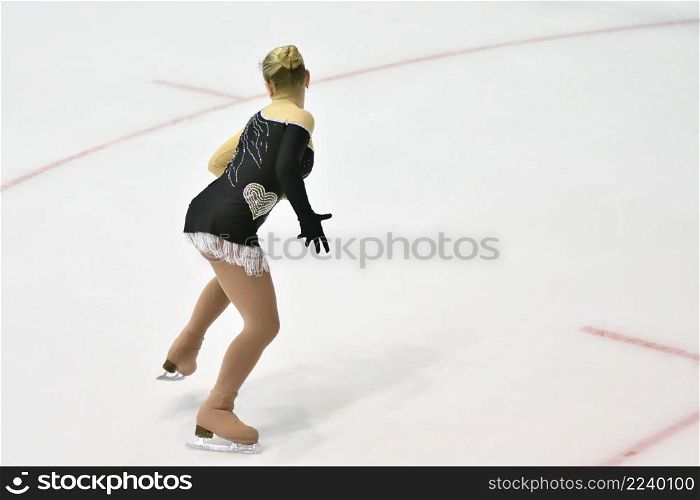 Girl figure skater rolls on a skating rink with artificial ice