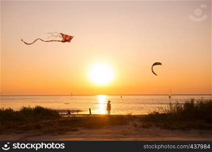 girl flying a kite on the sea in sunset time