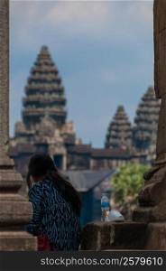 Girl from behind sitting in front of Angkor Wat. Girl from behind sitting in front of Angkor Wat in the morning