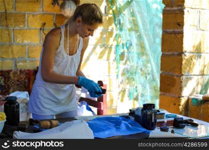 Girl gets pattern on the fabric paint in a rural workshop