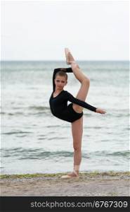 Girl gymnast in black. Cute little girl gymnast in black posing against the sea