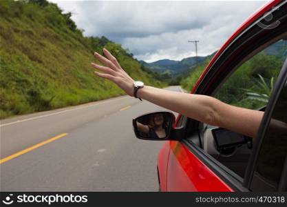 girl hand at the car window on an empty country road