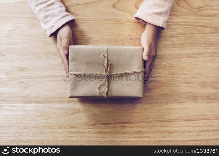 girl hand holding gift box on wood table background