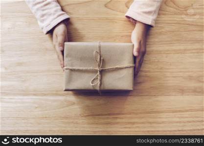 girl hand holding gift box on wood table background
