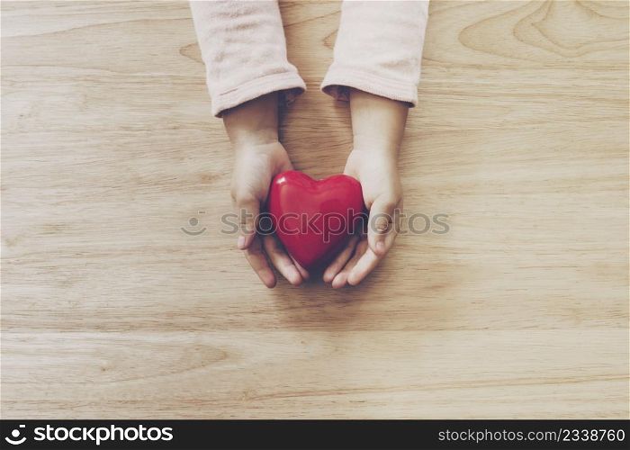 girl hand holding heart on wood table background