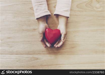 girl hand holding heart on wood table background