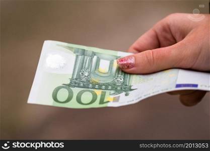 Girl hands giving money. Holding EURO banknotes on a blurred background