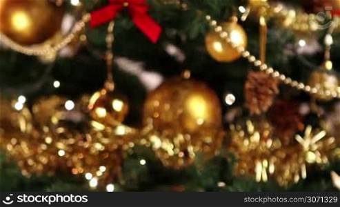 Girl hanging decorative ball on Christmas tree branch.