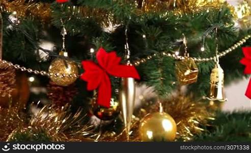 Girl hanging decorative ball on Christmas tree branch.