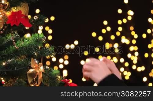 Girl hanging decorative ball on Christmas tree branch. Dolly shot