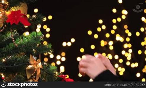 Girl hanging decorative ball on Christmas tree branch. Dolly shot