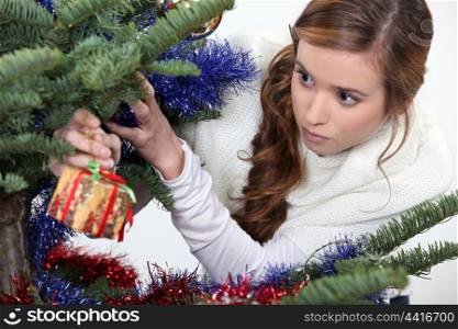 Girl hanging gift from Christmas tree