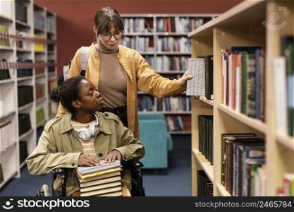 girl helping her colleague wheelchair choose book project 2