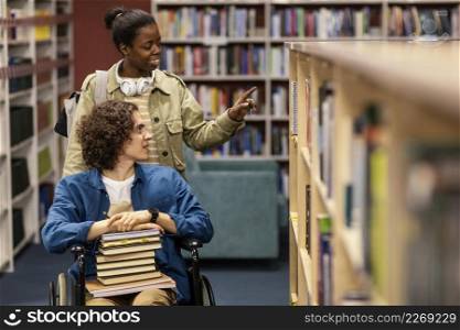 girl helping her colleague wheelchair choose book project
