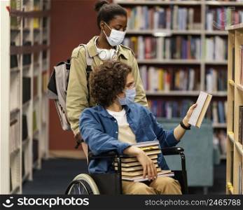 girl helping her colleague wheelchair choose his books library