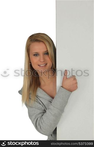 Girl hiding behind panel, studio shot