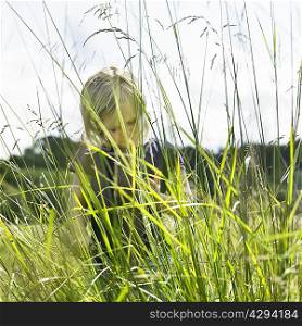Girl hiding behind tall grass