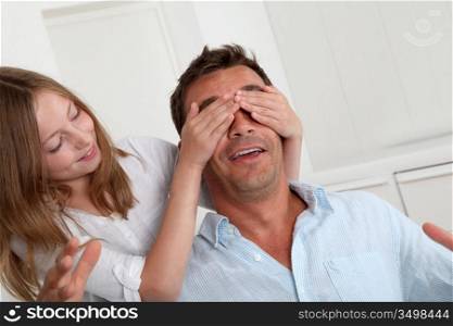 Girl hiding her father&acute;s eyes