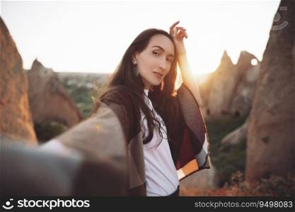 girl hiker in poncho on top of mountain at sunset