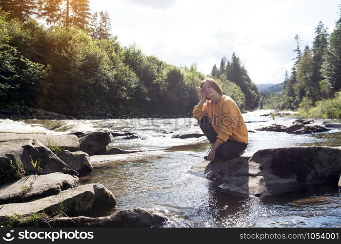 girl hiker on the bank of a mountain river