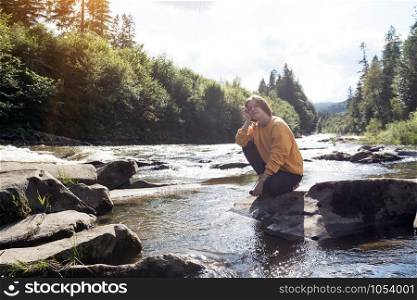 girl hiker on the bank of a mountain river