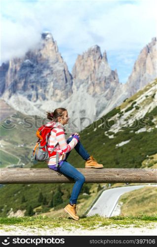 girl hiker sitting and looking at the snowed mountains. Dolomites, Italy.