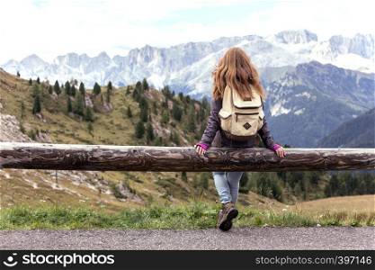 girl hiker sitting and looking at the snowed mountains. Dolomites, Italy.