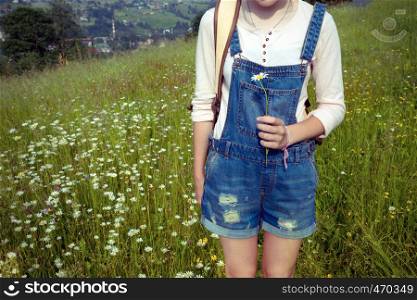 girl hiker with a backpack at the mountains with chamomile in hand. Vorokhta - Ukrainian landscape.