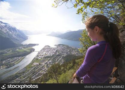girl hiker with a backpack looking on Romsdalsfjorden and Andalsnes, Norway