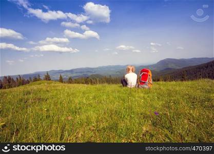 girl hiker with a backpack sitting on the background of mountains and forests. Vorokhta - Ukrainian landscape.