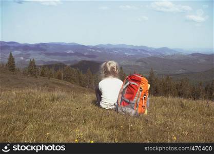 girl hiker with a backpack sitting on the background of mountains and forests. Vorokhta - Ukrainian landscape.