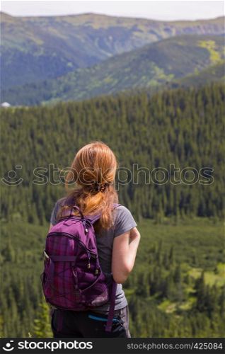 girl hiker with a backpack standing on the background of mountains and forests. Vorokhta - Ukrainian landscape.