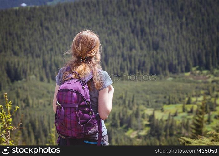 girl hiker with a backpack standing on the background of mountains and forests. Vorokhta - Ukrainian landscape.