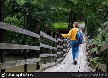 girl hiker with a backpack standing on the suspension bridge
