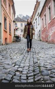girl hipster walking at the beautiful street in the old town of Sighisoara, Romania