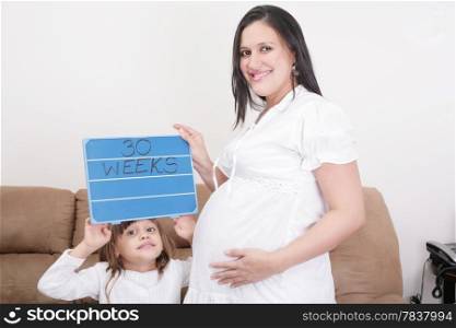 Girl holding a 30 weeks sign to her expectant mother