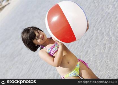 Girl holding a beach ball on the beach