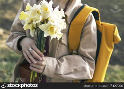 girl holding a bouquet of daffodils in her hands. atmospheric background outdoors 