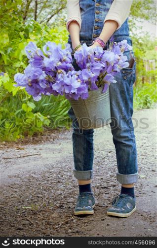 girl holding a bucket in the garden with irises