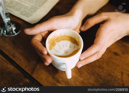 Girl holding a hot cup of coffee on the table. Girl holding a hot cup of coffee