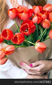 girl holding a huge bouquet of red tulips in their hands