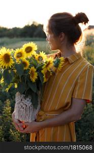 girl holding a huge bouquet of sunflowers in their hands in the sunset light