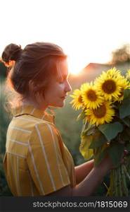 girl holding a huge bouquet of sunflowers in their hands in the sunset light