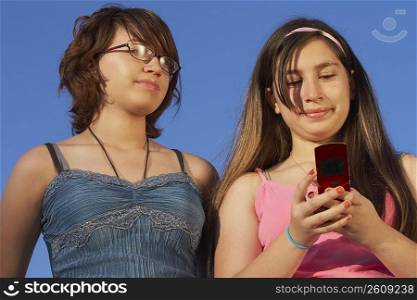 Girl holding a mobile phone and standing with a teenage girl